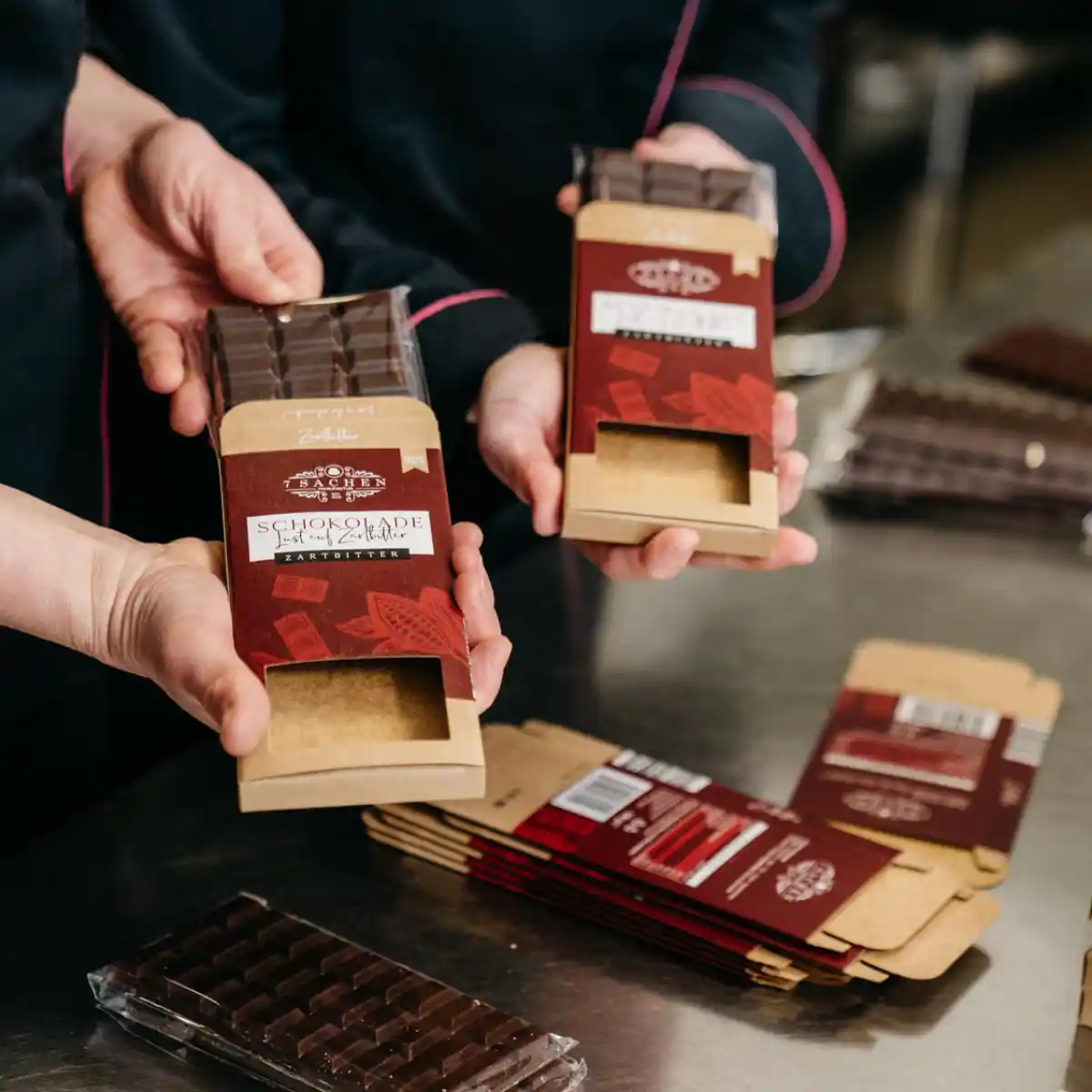 Verpackung handgegossener Schokoladentafeln in der 7 Sachen Manufaktur: nachhaltige Kartonhüllen in abgestimmten Farben, liebevoll von Hand gefertigt.