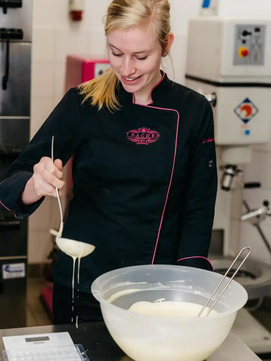 Handwerk in der 7 Sachen Manufaktur: Eine Mitarbeiterin gießt flüssige Schokolade – echte Handarbeit in Steinhagen.