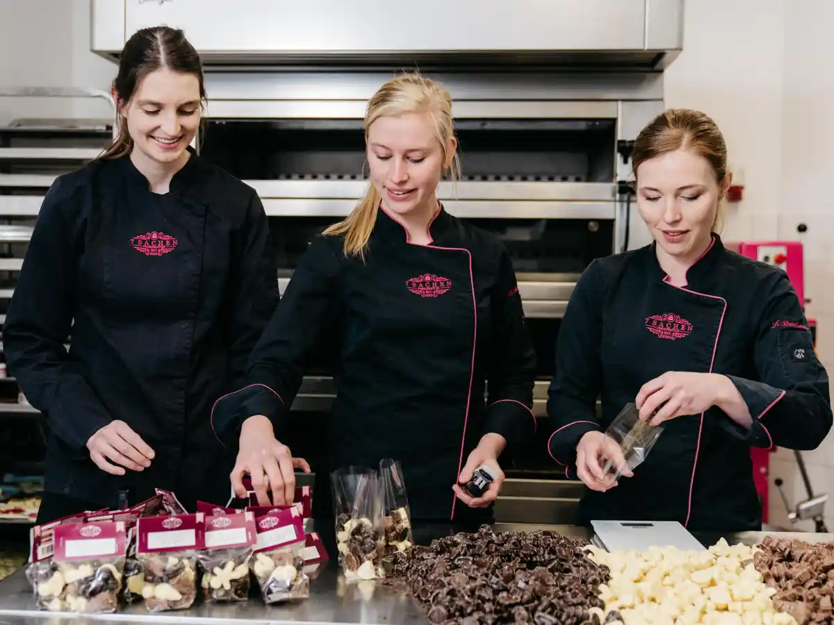 Team der 7 Sachen Manufaktur in Steinhagen beim Verpacken handgefertigter Schokoladenstücke – echte Handarbeit mit Liebe zum Detail.